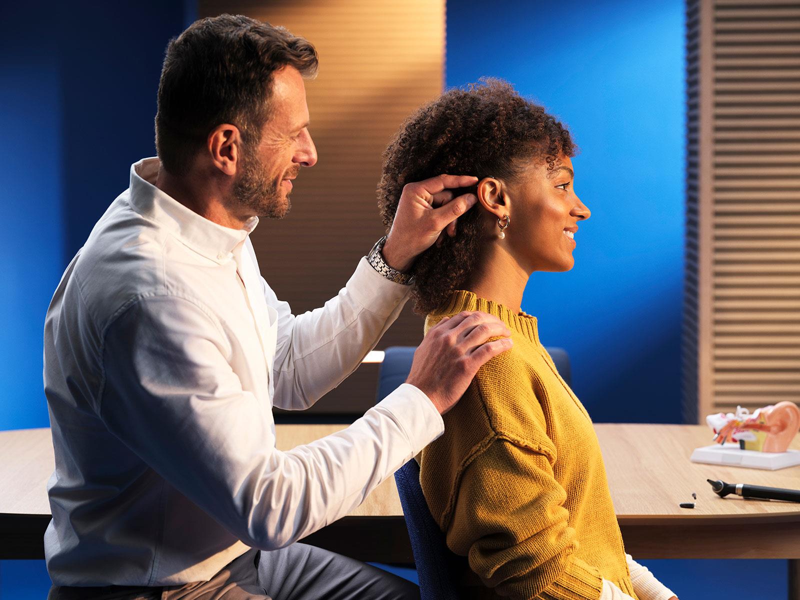 HCP fitting a woman with a hearing aid