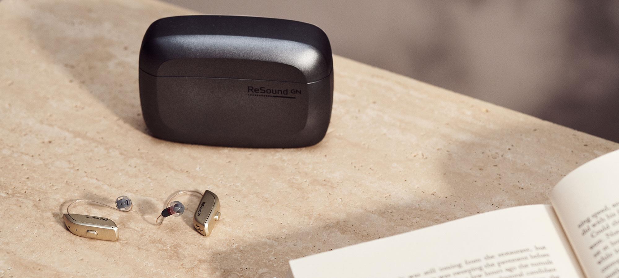 ReSound ONE on a table next to a charging case